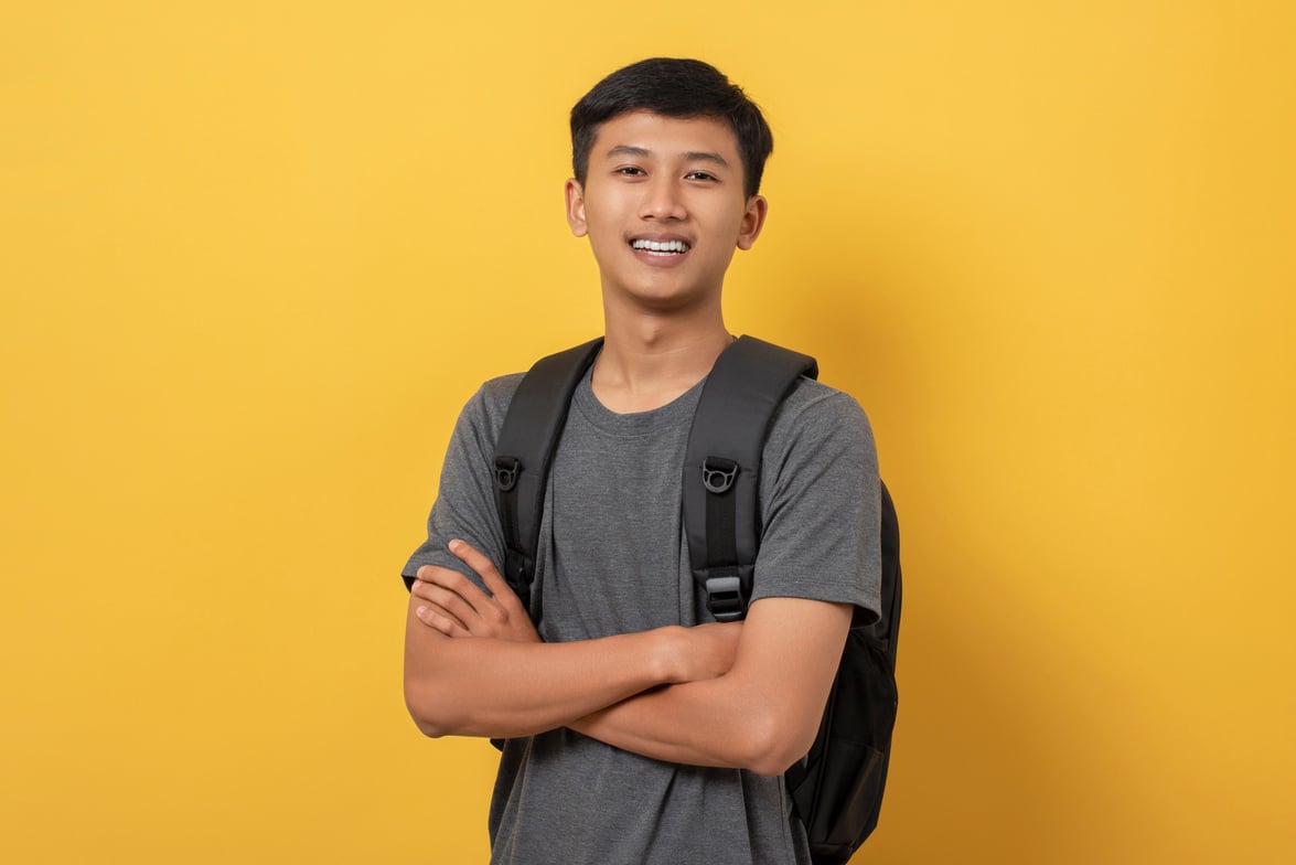 smiling confident young college student with books and backpack